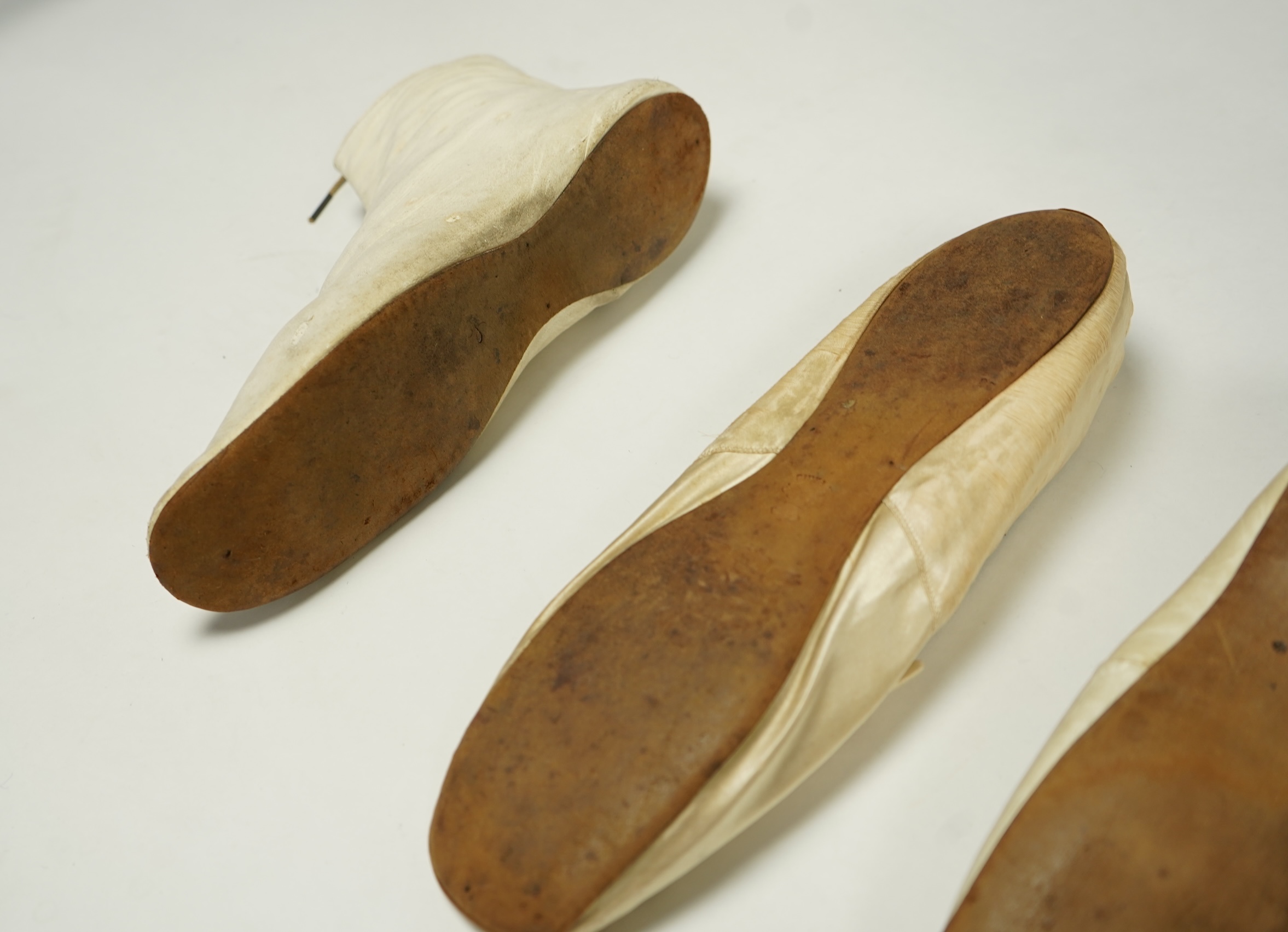 A 19th century hand made cream kid leather ladies ankle boot and four differing cream silk and satin single wedding shoes. All with leather soles. Possibly a traveller's sample range. Boots 24.5cm long (heel to toe). Con